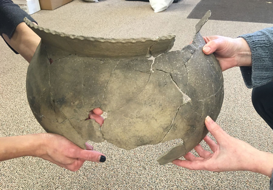 two women hold re-assembled vessel